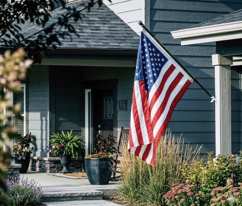 Veranda eines Hauses mit gehisster US-Flagge, Blumentöpfen und Eingangsbereich